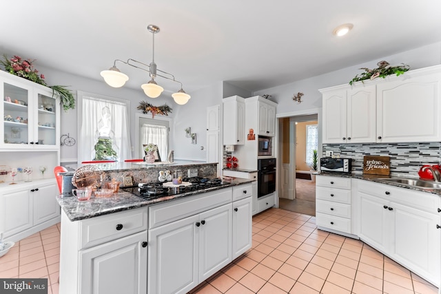 kitchen with hanging light fixtures, glass insert cabinets, white cabinets, a sink, and black appliances