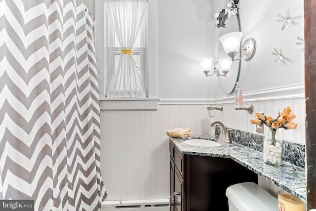 bathroom with a baseboard radiator, toilet, a wainscoted wall, a shower with shower curtain, and vanity