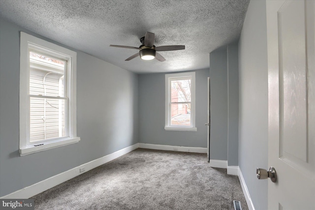 unfurnished room with visible vents, a ceiling fan, carpet flooring, a textured ceiling, and baseboards
