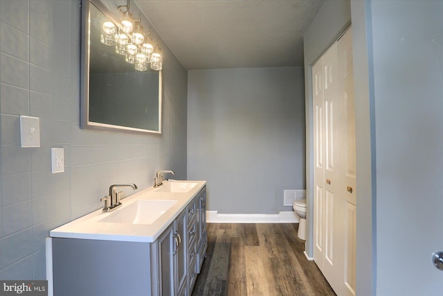 full bath with toilet, visible vents, a sink, and wood finished floors
