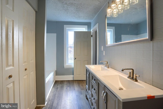 full bath featuring a textured ceiling, wood finished floors, a sink, and tasteful backsplash