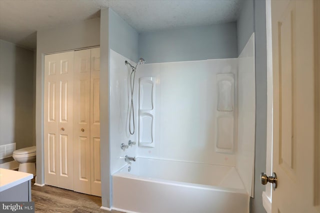 bathroom with a textured ceiling, toilet, wood finished floors, vanity, and shower / bathing tub combination