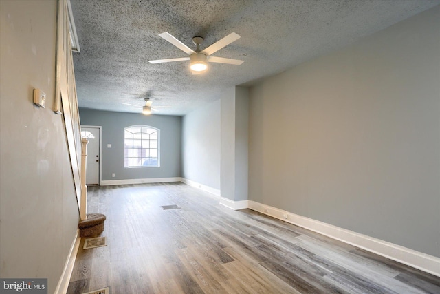 spare room featuring visible vents, baseboards, ceiling fan, wood finished floors, and a textured ceiling