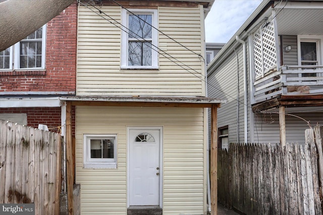back of house featuring brick siding and fence