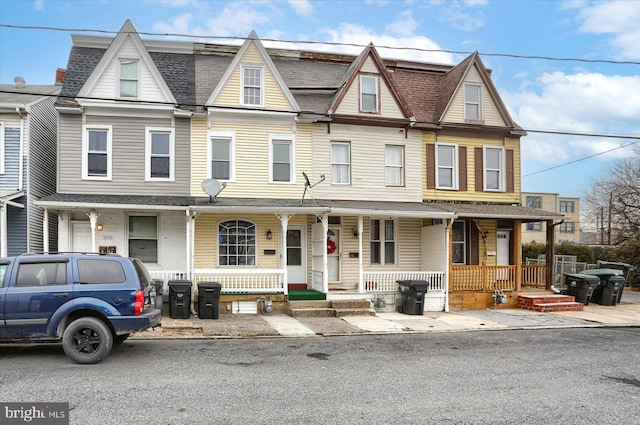 townhome / multi-family property with a porch and a shingled roof