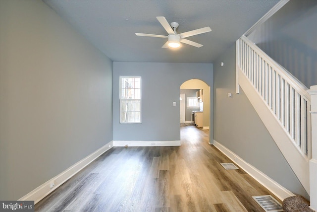spare room with stairs, visible vents, arched walkways, and wood finished floors