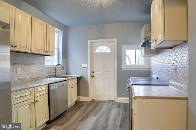 kitchen with light countertops, light wood-style flooring, cream cabinets, appliances with stainless steel finishes, and a sink