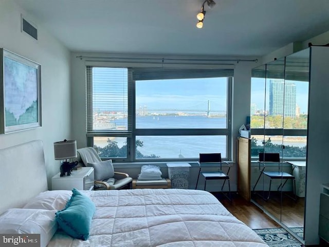 bedroom featuring multiple windows, wood finished floors, and visible vents