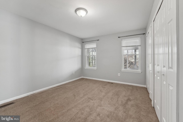 unfurnished bedroom featuring baseboards, visible vents, a closet, and carpet flooring