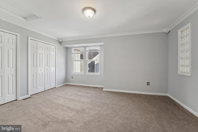 unfurnished bedroom featuring crown molding, baseboards, carpet flooring, and multiple closets