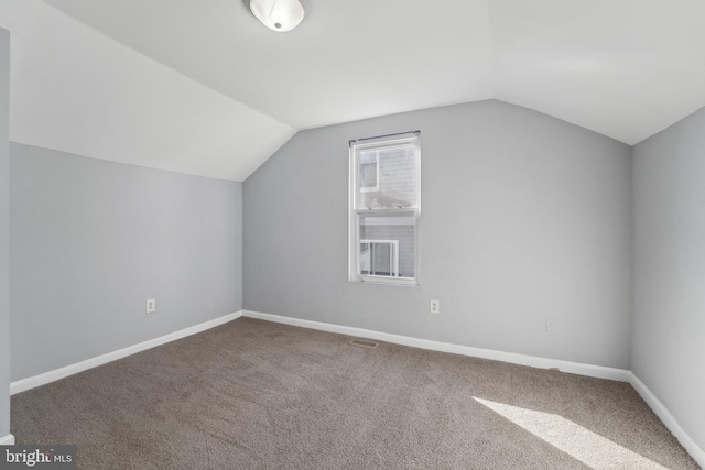 additional living space featuring lofted ceiling, baseboards, visible vents, and carpet flooring