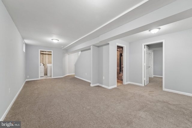 finished below grade area featuring carpet floors, baseboards, and washing machine and clothes dryer