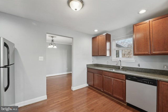 kitchen with light wood-style flooring, freestanding refrigerator, a sink, dishwasher, and baseboards