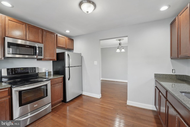 kitchen with appliances with stainless steel finishes, wood-type flooring, recessed lighting, and baseboards