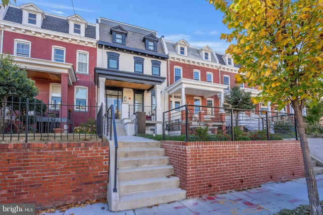 victorian home with mansard roof, a residential view, and brick siding