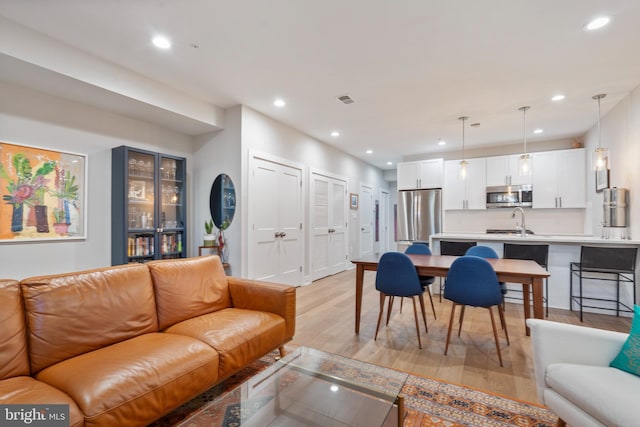 living room featuring light wood-type flooring, visible vents, and recessed lighting