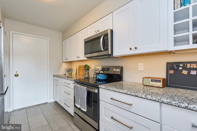 kitchen featuring light stone counters, appliances with stainless steel finishes, light tile patterned flooring, and white cabinetry