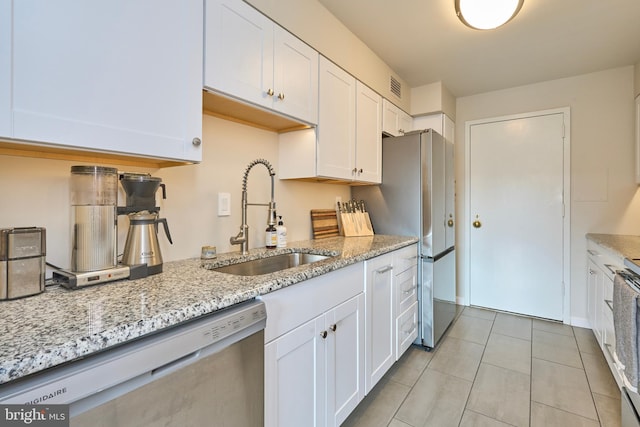 kitchen featuring visible vents, white cabinets, light stone counters, appliances with stainless steel finishes, and a sink