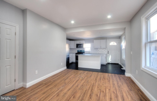 kitchen featuring dark wood-style flooring, stainless steel appliances, light countertops, white cabinetry, and baseboards