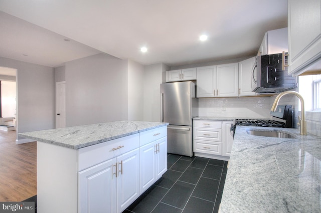 kitchen featuring stainless steel appliances, tasteful backsplash, white cabinetry, a sink, and light stone countertops