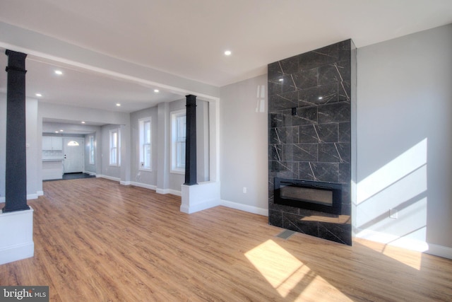 unfurnished living room with a premium fireplace, baseboards, wood finished floors, and recessed lighting