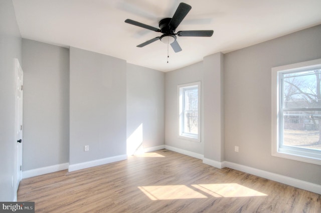 spare room with a wealth of natural light, light wood-style flooring, and baseboards