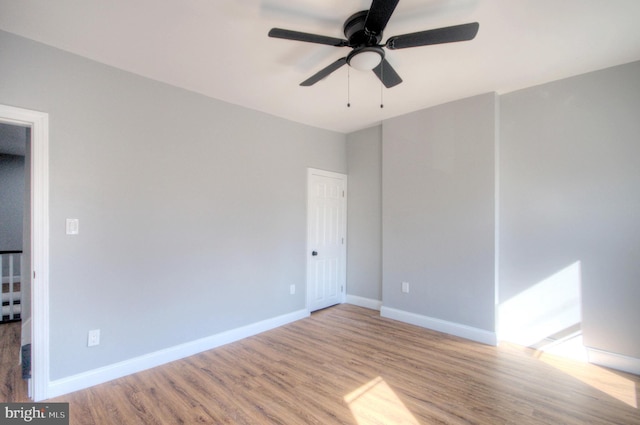 spare room featuring light wood-style floors, ceiling fan, and baseboards