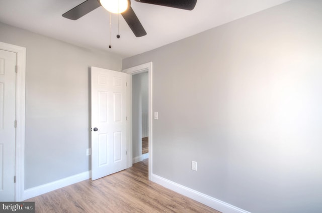 unfurnished bedroom with a ceiling fan, light wood-type flooring, and baseboards