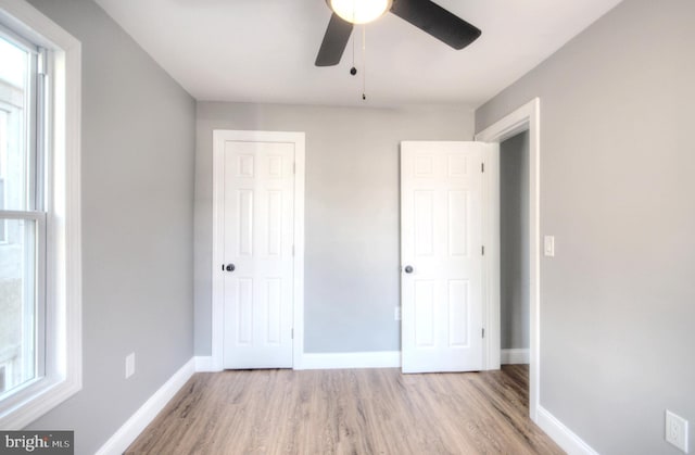 unfurnished bedroom with a ceiling fan, a closet, light wood-style flooring, and baseboards