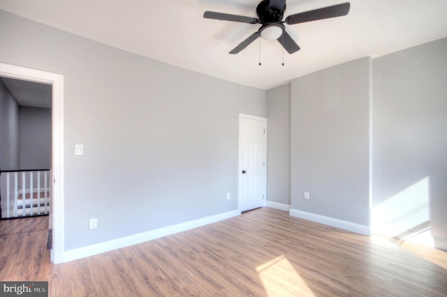 unfurnished room with ceiling fan, baseboards, and wood finished floors