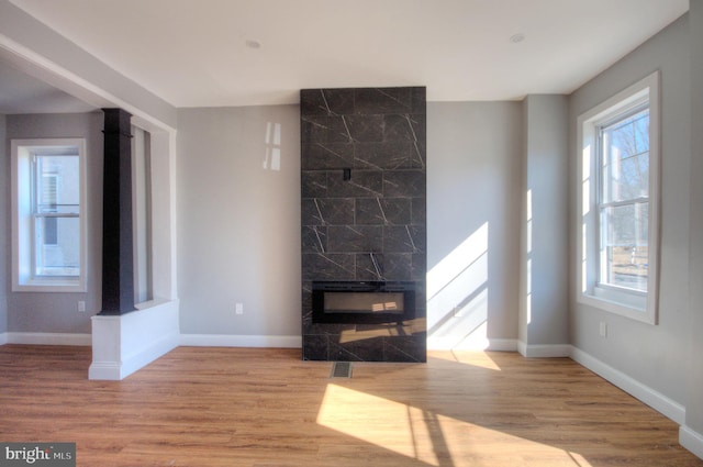 unfurnished living room featuring light wood finished floors, visible vents, a premium fireplace, and baseboards