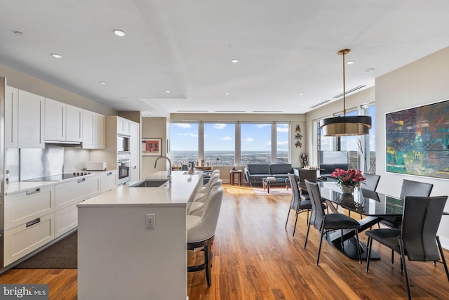 kitchen with a sink, white cabinetry, light countertops, appliances with stainless steel finishes, and decorative light fixtures