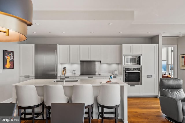 kitchen featuring stainless steel appliances, a sink, white cabinetry, and light stone countertops