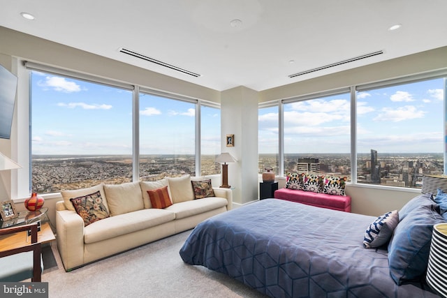 bedroom with a view of city, visible vents, light colored carpet, and recessed lighting