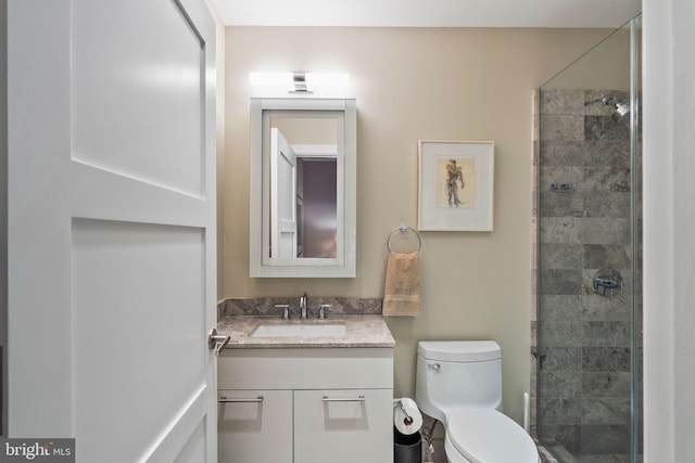 full bath featuring tiled shower, vanity, and toilet