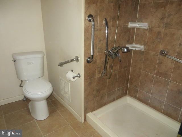 bathroom with visible vents, toilet, a stall shower, tile patterned flooring, and baseboards