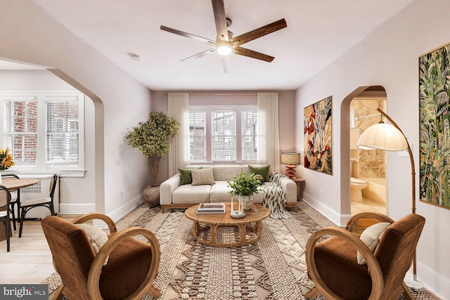 sitting room featuring baseboards, arched walkways, and ceiling fan