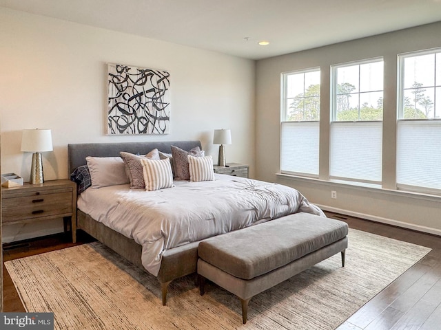 bedroom featuring multiple windows, baseboards, and wood finished floors