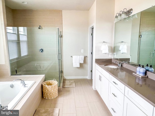 full bath featuring a garden tub, vanity, baseboards, and a stall shower