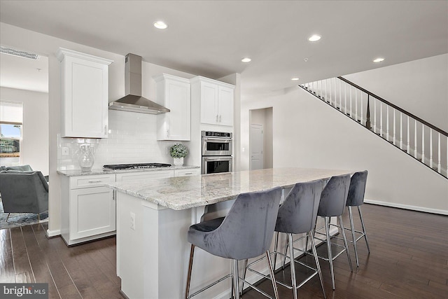 kitchen with stainless steel appliances, white cabinets, wall chimney range hood, backsplash, and dark wood-style floors