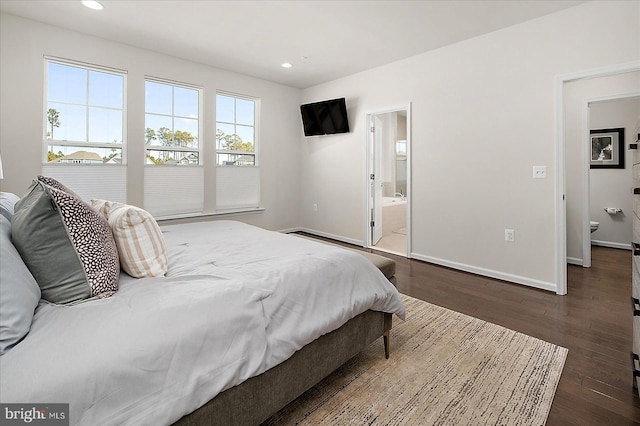 bedroom with ensuite bathroom, dark wood-style flooring, recessed lighting, and baseboards