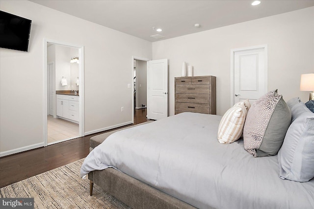 bedroom featuring baseboards, a sink, wood finished floors, and recessed lighting