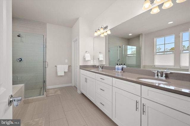 bathroom with double vanity, a shower stall, baseboards, and a sink