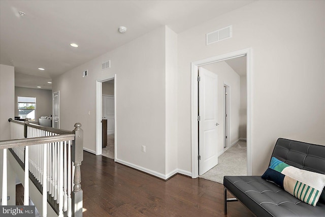 hallway featuring visible vents, an upstairs landing, and wood finished floors