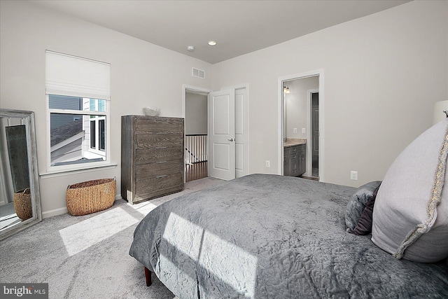 carpeted bedroom with baseboards, visible vents, and connected bathroom