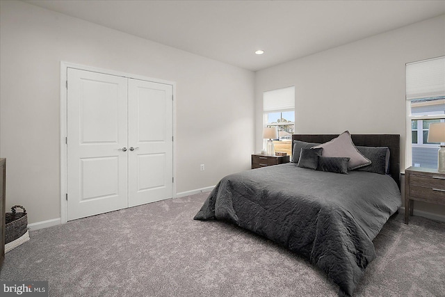 bedroom with a closet, multiple windows, baseboards, and carpet flooring