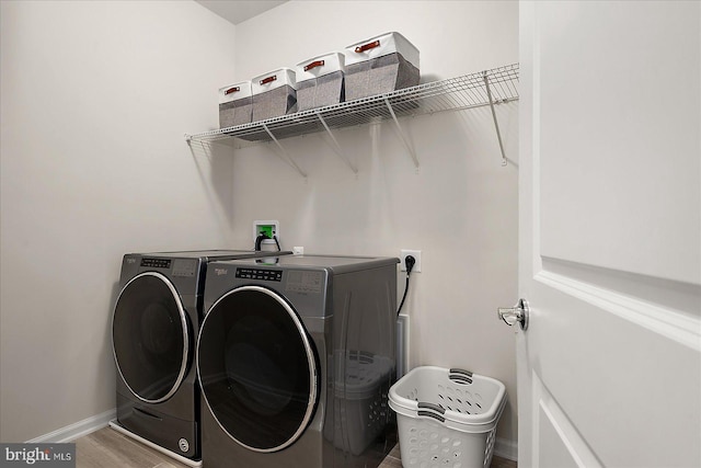 washroom with laundry area, separate washer and dryer, wood finished floors, and baseboards