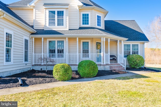 view of front of property featuring a porch, a front lawn, and a shingled roof