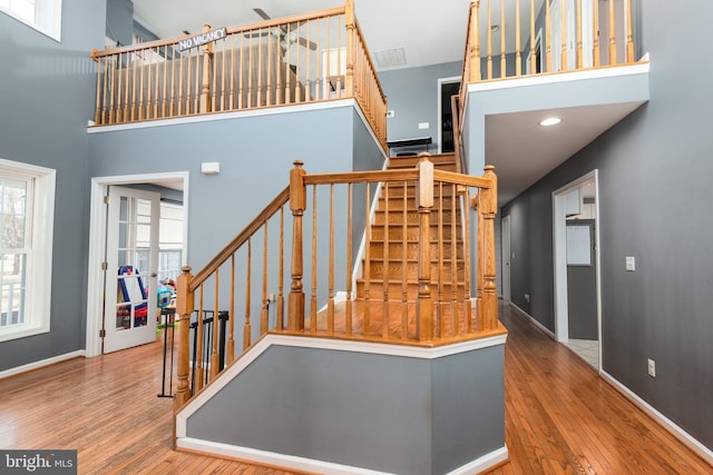 stairway featuring a high ceiling, wood finished floors, and baseboards