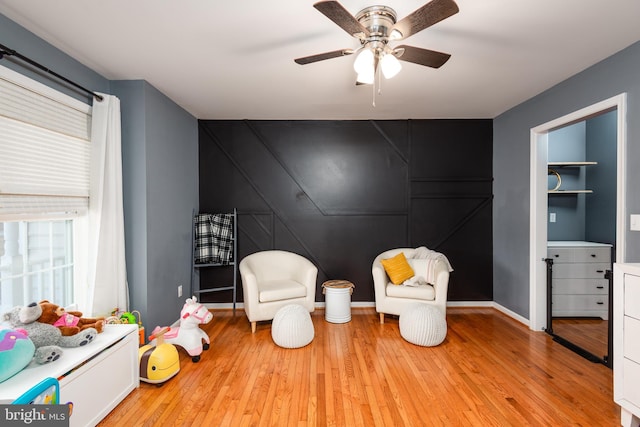 sitting room with light wood-style floors, baseboards, and a ceiling fan